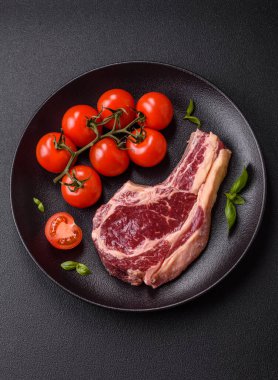 Taze, çiğ biftek, tuz, baharat ve otlar koyu dokulu arka planda.