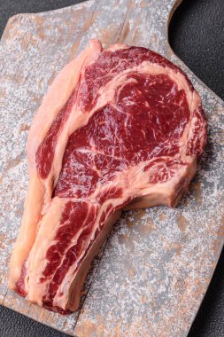 Taze, çiğ biftek, tuz, baharat ve otlar koyu dokulu arka planda.