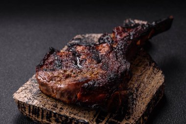 Koyu beton arka planda tuzlu, baharatlı ve otlu sulu ızgara baltalı biftek.