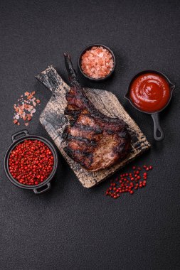 Koyu beton arka planda tuzlu, baharatlı ve otlu sulu ızgara baltalı biftek.