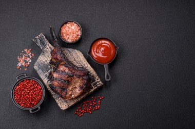 Koyu beton arka planda tuzlu, baharatlı ve otlu sulu ızgara baltalı biftek.