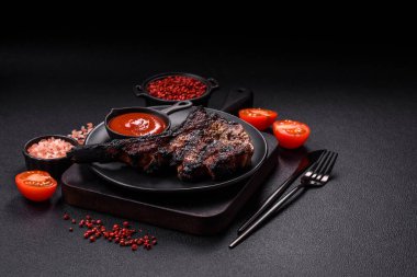 Koyu beton arka planda tuzlu, baharatlı ve otlu sulu ızgara baltalı biftek.