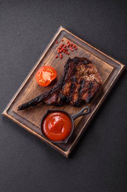 Koyu beton arka planda tuzlu, baharatlı ve otlu sulu ızgara baltalı biftek.