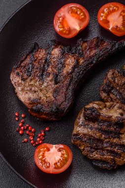 Koyu beton arka planda tuzlu, baharatlı ve otlu sulu ızgara baltalı biftek.