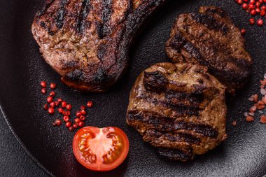 Koyu beton arka planda tuzlu, baharatlı ve otlu sulu ızgara baltalı biftek.