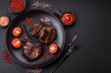 Koyu beton arka planda tuzlu, baharatlı ve otlu sulu ızgara baltalı biftek.