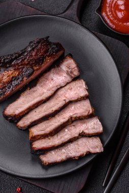 Koyu beton arka planda tuzlu, baharatlı ve otlu sulu ızgara baltalı biftek.