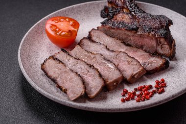 Koyu beton arka planda tuzlu, baharatlı ve otlu sulu ızgara baltalı biftek.