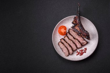 Koyu beton arka planda tuzlu, baharatlı ve otlu sulu ızgara baltalı biftek.