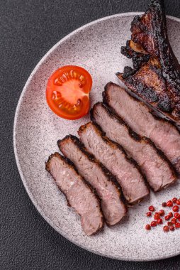 Koyu beton arka planda tuzlu, baharatlı ve otlu sulu ızgara baltalı biftek.