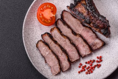 Koyu beton arka planda tuzlu, baharatlı ve otlu sulu ızgara baltalı biftek.