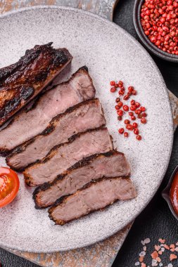 Koyu beton arka planda tuzlu, baharatlı ve otlu sulu ızgara baltalı biftek.