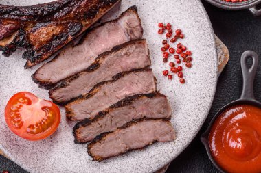 Koyu beton arka planda tuzlu, baharatlı ve otlu sulu ızgara baltalı biftek.