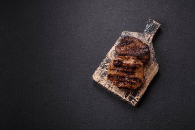 Karanlık bir arka planda taze sulu lezzetli biftek. Baharatlı ve otlu et yemeği.