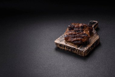 Karanlık bir arka planda taze sulu lezzetli biftek. Baharatlı ve otlu et yemeği.