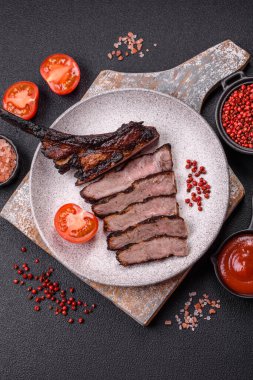 Koyu beton arka planda tuzlu, baharatlı ve otlu sulu ızgara baltalı biftek.