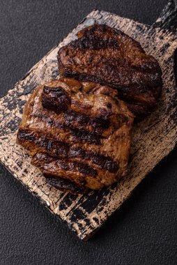 Karanlık bir arka planda taze sulu lezzetli biftek. Baharatlı ve otlu et yemeği.