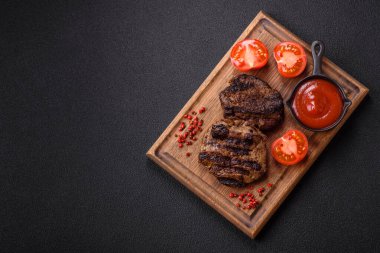 Karanlık bir arka planda taze sulu lezzetli biftek. Baharatlı ve otlu et yemeği.