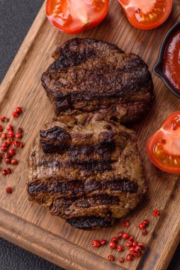 Karanlık bir arka planda taze sulu lezzetli biftek. Baharatlı ve otlu et yemeği.