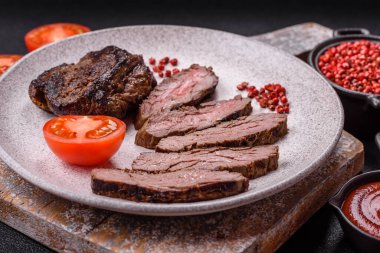 Karanlık bir arka planda taze sulu lezzetli biftek. Baharatlı ve otlu et yemeği.