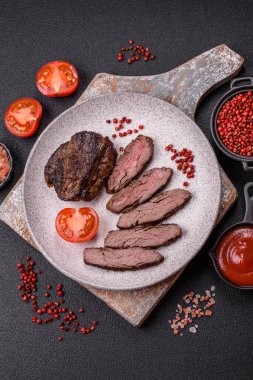 Karanlık bir arka planda taze sulu lezzetli biftek. Baharatlı ve otlu et yemeği.