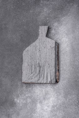 Empty wooden cutting board on dark textured concrete background. Cutlery, preparation for dinner