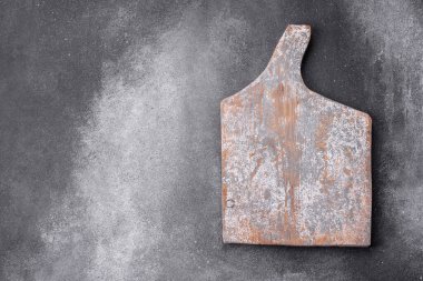 Empty wooden cutting board on dark textured concrete background. Cutlery, preparation for dinner