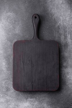 Empty wooden cutting board on dark textured concrete background. Cutlery, preparation for dinner