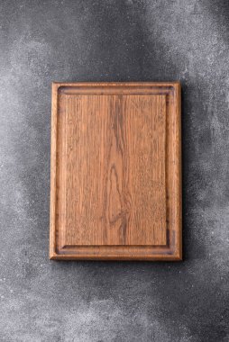 Empty wooden cutting board on dark textured concrete background. Cutlery, preparation for dinner