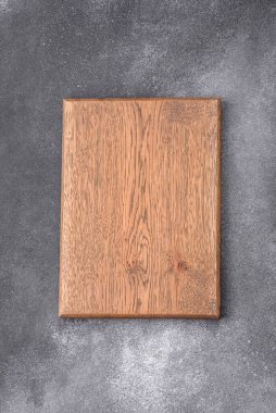 Empty wooden cutting board on dark textured concrete background. Cutlery, preparation for dinner