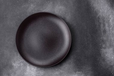 Koyu dokulu arka planda boş seramik tabak. Aile yemeği için mutfak gereçleri hazırlıyorum.