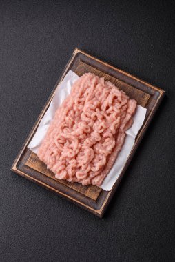 Koyu beton arka planda tuz ve baharatlı taze çiğ tavuk kıyması.