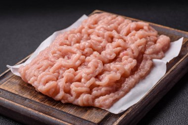 Koyu beton arka planda tuz ve baharatlı taze çiğ tavuk kıyması.