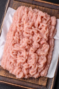 Koyu beton arka planda tuz ve baharatlı taze çiğ tavuk kıyması.