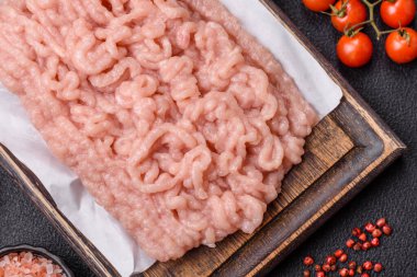 Koyu beton arka planda tuz ve baharatlı taze çiğ tavuk kıyması.