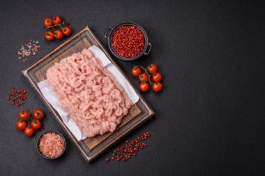 Koyu beton arka planda tuz ve baharatlı taze çiğ tavuk kıyması.