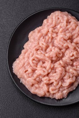 Koyu beton arka planda tuz ve baharatlı taze çiğ tavuk kıyması.