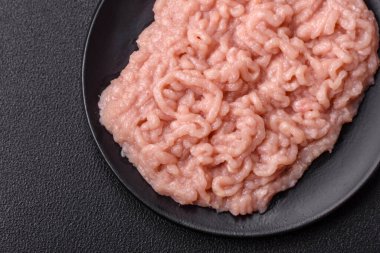 Koyu beton arka planda tuz ve baharatlı taze çiğ tavuk kıyması.