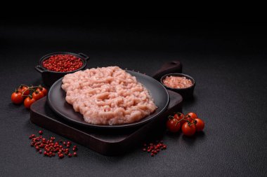 Koyu beton arka planda tuz ve baharatlı taze çiğ tavuk kıyması.