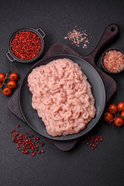 Koyu beton arka planda tuz ve baharatlı taze çiğ tavuk kıyması.