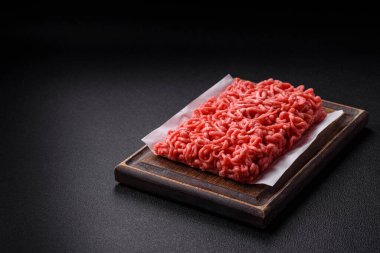 Koyu beton arka planda tuzlu ve baharatlı taze çiğ et.