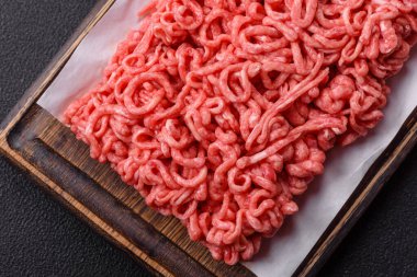 Koyu beton arka planda tuzlu ve baharatlı taze çiğ et.