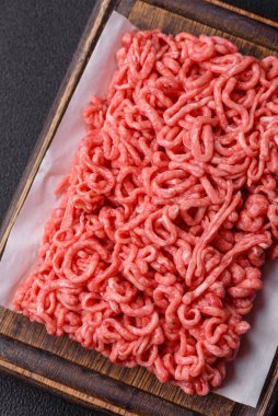 Koyu beton arka planda tuzlu ve baharatlı taze çiğ et.