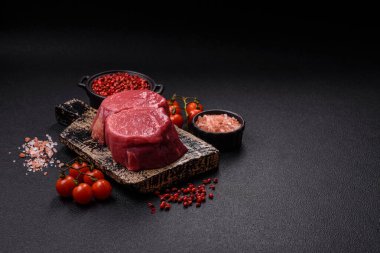 Koyu beton arka planda tuz ve baharatlı taze çiğ et madalyonları.