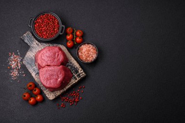 Koyu beton arka planda tuz ve baharatlı taze çiğ et madalyonları.