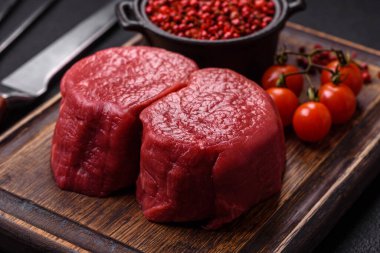 Koyu beton arka planda tuz ve baharatlı taze çiğ et madalyonları.