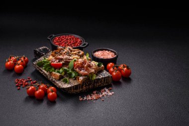 Koyu beton bir zemin üzerinde jambon, mantar ve dana eti, domates ve mikroçerez içeren çeşitli tostlar veya bruschetta çeşitleri