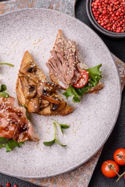 Koyu beton bir zemin üzerinde jambon, mantar ve dana eti, domates ve mikroçerez içeren çeşitli tostlar veya bruschetta çeşitleri