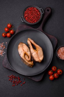 Lezzetli kırmızı somon balığı, çimento arka planda baharat ve otlarla kızartılmış.