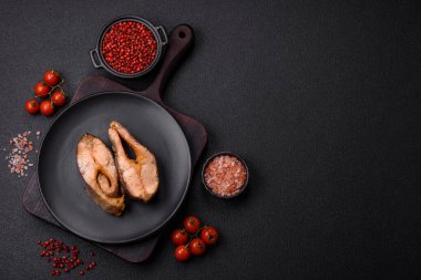 Lezzetli kırmızı somon balığı, çimento arka planda baharat ve otlarla kızartılmış.